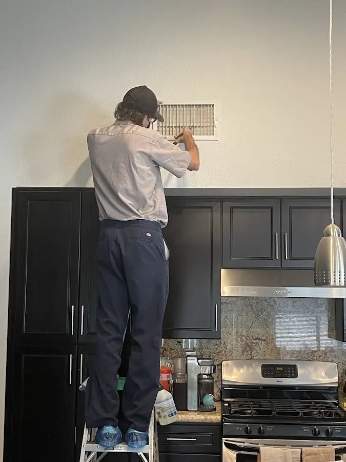 Technician inspecting an air vent during HVAC service in Kingfisher